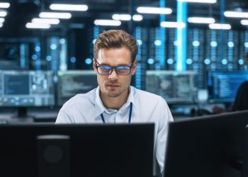 Night,Office:,Young,Caucasian,Man,Working,On,Two,Desktop,Computers.